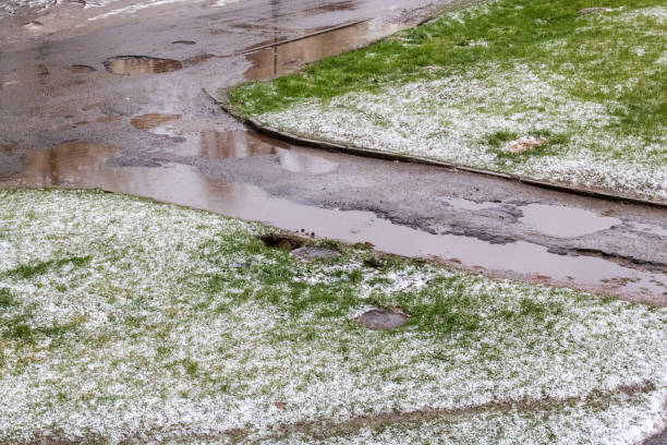istock Snow on green grass and puddle on road 1304314315