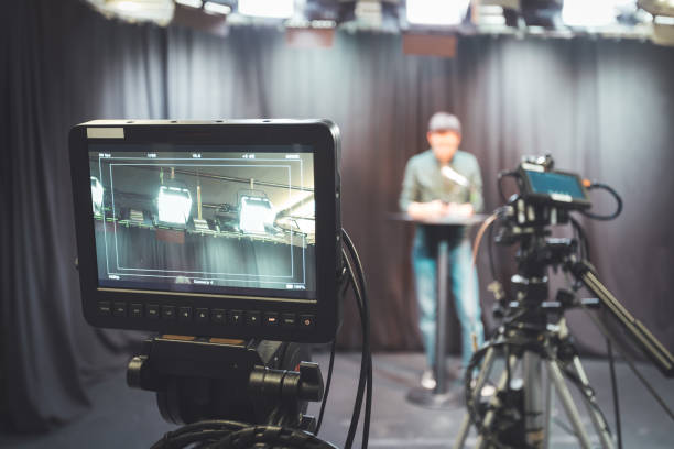 istock Young journalist in a television recording studio is talking into a microphone, blurry film cameras 1304319168