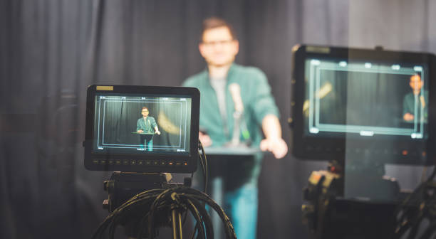 istock Young journalist in a television recording studio is talking into a microphone, blurry film cameras 1304319172