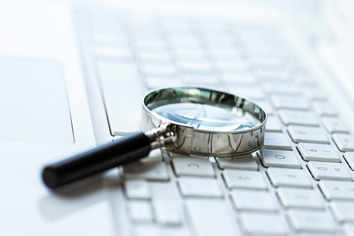 Magnifying glass on white laptop keyboard