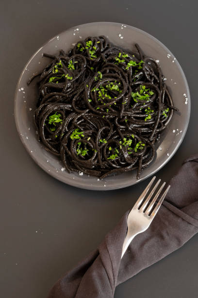 istock Black spaghetti pasta with Cuttlefish ink. Black seafood pasta on a dark background. Mediterranean delicacy food. 1304322032