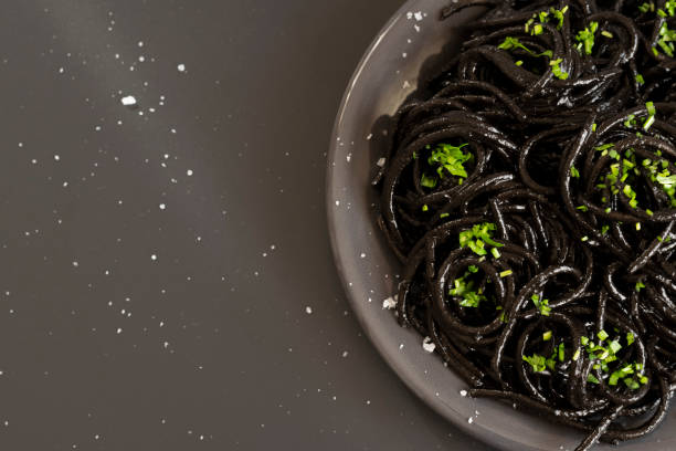 istock Black spaghetti pasta with Cuttlefish ink. Black seafood pasta on a dark background. Mediterranean delicacy food. 1304322036