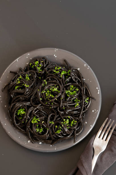 istock Black spaghetti pasta with Cuttlefish ink. Black seafood pasta on a dark background. Mediterranean delicacy food. 1304322040