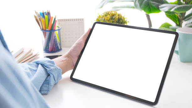 istock Close up of man hand holding digital tablet with blank screen on working table background for mock up, template 1304323233