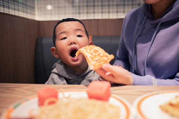 istock Baby boy eating pizza in restaurant 1304331104
