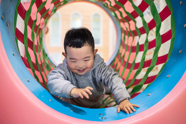 istock Baby boy climbing over in playground tunnel 1304331177