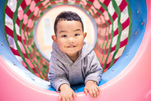 istock Baby boy climbing over in playground tunnel 1304331326