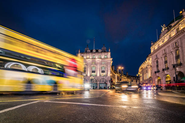 istock Evening illumination reflections with intense traffic passing the wet crossroads at Piccadilly Circus in London city, UK - creative stock image 1304331369