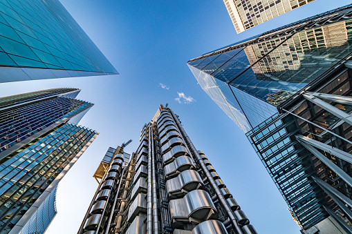 Highly detailed abstract wide angle view up towards the sky from a very low angle in the financial district of London City, UK and its ultra modern contemporary buildings with unique architecture on a bright sunny day. Shot on Canon EOS R full frame with 14mm wide prime lens for premium quality. Image is ideal for background with plenty of copy space for various concepts and ideas.
