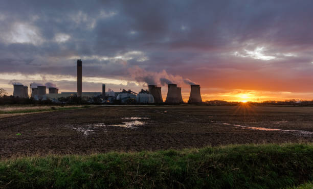 Sunrise over the village of Drax in North Yorkshire with plumes of water vapour rising from the cooling towers of a local Power Station. Early morning near Drax in North Yorkshire with the sun just about to rise in the East. Plumes of water vapour rising from the cooling towers of a local Power Station. Horizontal.  Space for copy. extinction rebellion photos stock pictures, royalty-free photos & images