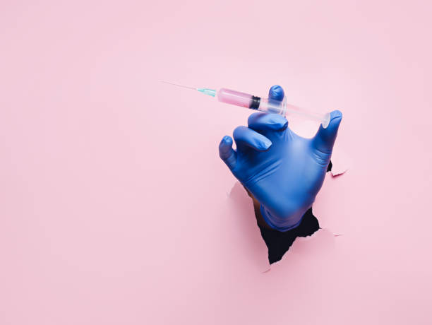 istock Hand with syringe breaking in through a black hole on yellow background 1304333372