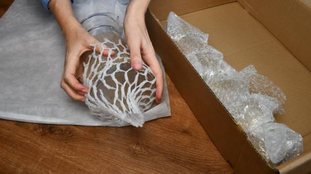 istock Female hands packing up glass jug into wrapping mesh to protect while moving 1304334885