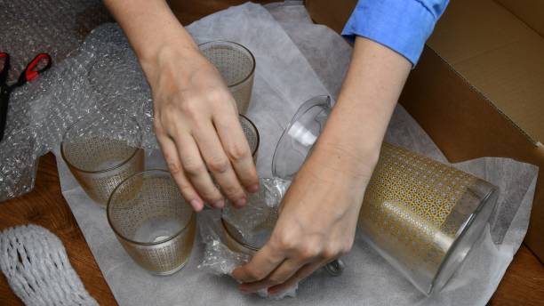 istock Packing up glassware into plastic bubble wrapping and cardboard box 1304334889
