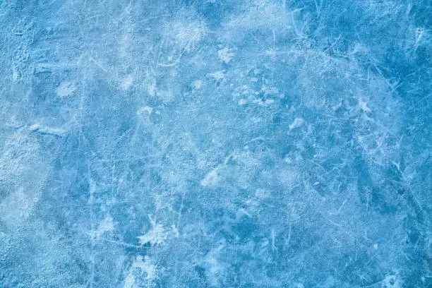 Photo of Ice blue background with ice skating tracks.