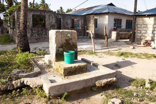 Water well inside of african village. Plastic bucket under the faucet.