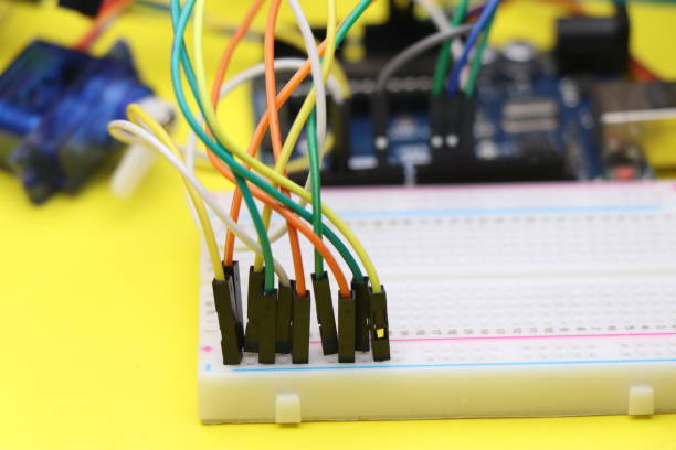 istock Science projects or electronics project concept shown by connecting jumper wires to breadboard with some electronic components on the background. Electronics project concept on yellow background 1304348689