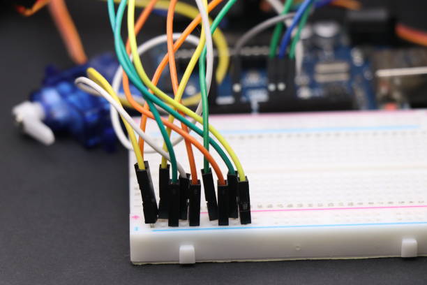 istock Science projects or electronics project concept shown by connecting jumper wires to breadboard with some electronic components on the background. Electronics project concept 1304348699