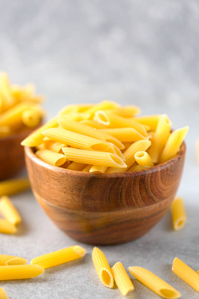 istock Bowl of raw penne pasta on ultimate gray background 1304348974