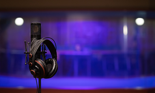 image of a condenser microphone on a boom stand, with black headphones.