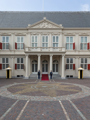 The Hague, South-Holland, The Netherlands, june 24th 2015, facade and entrance of Noordeinde palace as seen from the street in front of the palace, two guards are standing on each side of the door - Noordeinde is national heritage site ('rijksmonument') and has been King Willem Alexander's place of work since 2013