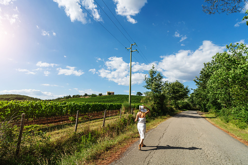 summer in Italy: Woman walking in Vineyards of Chianti and Val D'Orcia in Tuscany, Italy