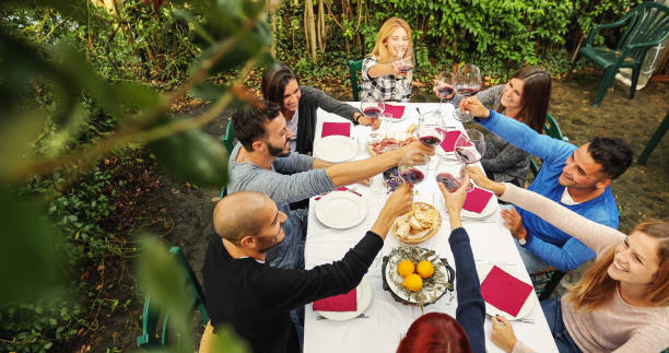 Friends together enjoy meal and red wine: up the glasses Friends together enjoy meal and red wine in Italy agritourism stock pictures, royalty-free photos & images