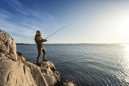 Man spinning fishing in the sea with a rod, from the rocks