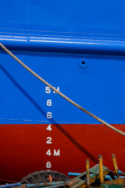 istock Draft mark numbers on blue and red rust proof vessel hull with mooring rope and rusty metal scraps pile at shipyard 1304357675