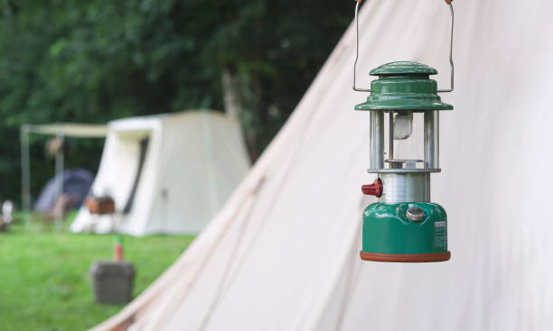 foco no acampamento lanterna de acetileno com fundo desfocado de tendas de campo em área de camping em parkland natural - acetylene - fotografias e filmes do acervo