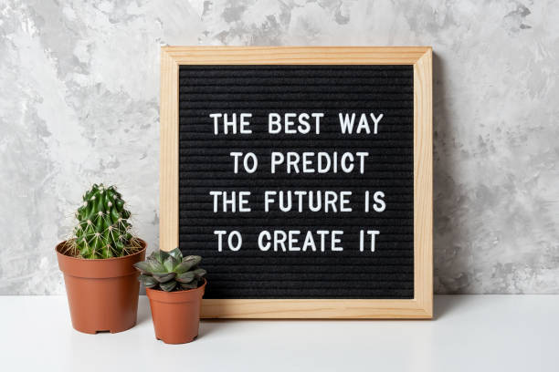 The best way to predict the future is to create it. Motivational quote on letter board, cactus, succulent flower on white table. Concept inspirational quote of the day. Front view stock photo