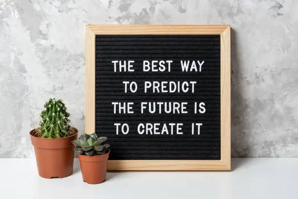 The best way to predict the future is to create it. Motivational quote on letter board, cactus, succulent flower on white table. Concept inspirational quote of the day. Front view.