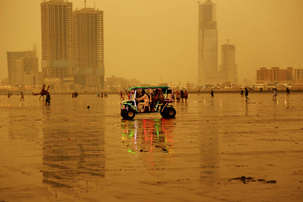 Locals riding beach buggy illuminated with LED lights at Clifton Beach, Karachi Karachi – Pakistan: Karachites at Clifton Beach enjoying sunset with decorated camels for rides at Clifton - Karachi’s most famous beach. Camel rides are famous among tourists visiting Clifton beach. clifton stock pictures, royalty-free photos & images