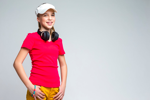 Youth Lifestyle. Portrait of Happy Smiling Caucasian Teenage Girl with Wireless Headphones. Posing Over Gray background. Horizontal Image