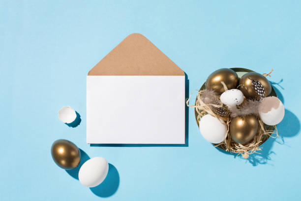 istock Easter golden eggs, quail eggs, feathers and empty white card on blue background. Copy space, top view. 1304367465