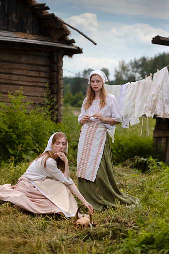 Two Lovely Country Girls Posing Together in Countryside Environment Outdoor With Linens Sheets Hanged On Rope Behind.