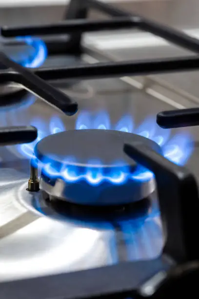 Photo of Gas Ideas and Concepts. Macro Shoot of Gas Burner on Stove Surface with Fire Flames. Vertical image