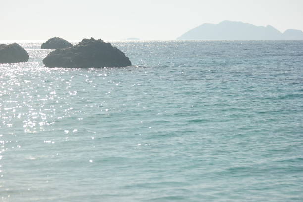 Seascape background with a rocks on a summer day. Calm sea and stones with clear sky in the background.