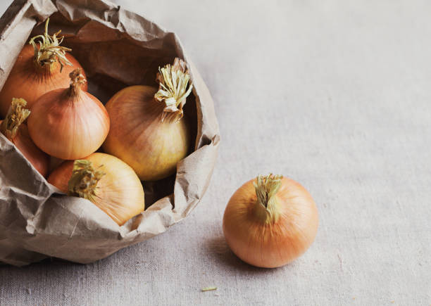 Fresh brown onion in a paper bag on a black table, top view