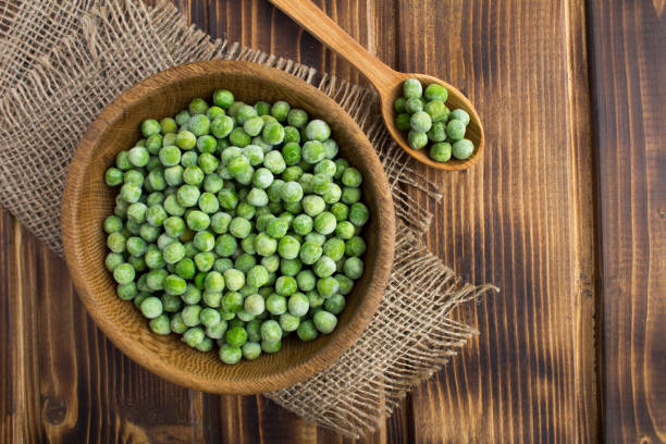istock Frozen peas  in the brown bowl  on the  rustic wooden background 1304375268