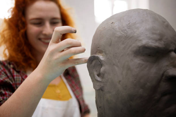 istock Young smiling redhead woman working on a head sculpture 1304380667