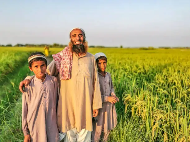 Asian Farmer with his two sons standing between his fields