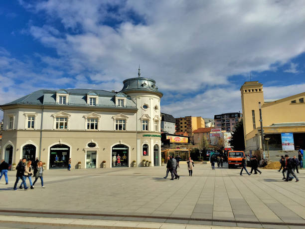 People are walking over a pedestrian place on a sunny day and buildings in the background in the city of Pristina in Kosovo March 25,2016