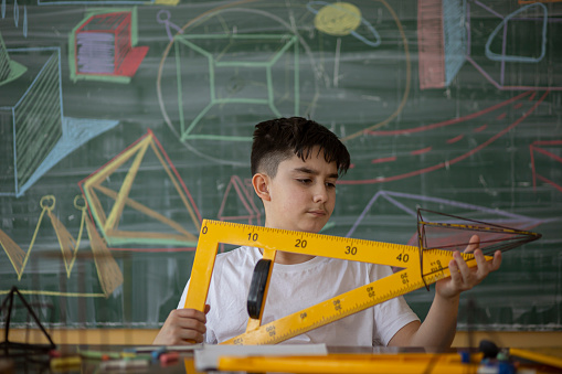 Boy sitting at school holding yellow ruler.