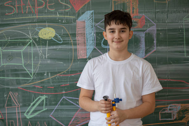 School boy standing in front of the board and looking at camera.