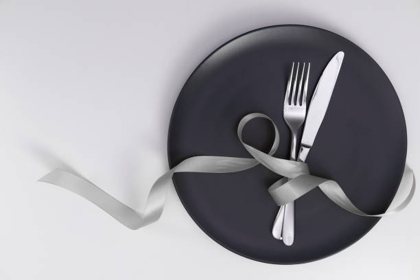 istock Table setting with gray plate and ribbon. Fork and knife for a holiday dinner on a holiday date. Place for taeksta on a white background. 1304387275