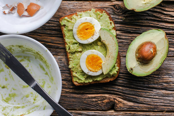 istock Toast with mashed avocado and eggs on messy rustic wooden table from above 1304387425