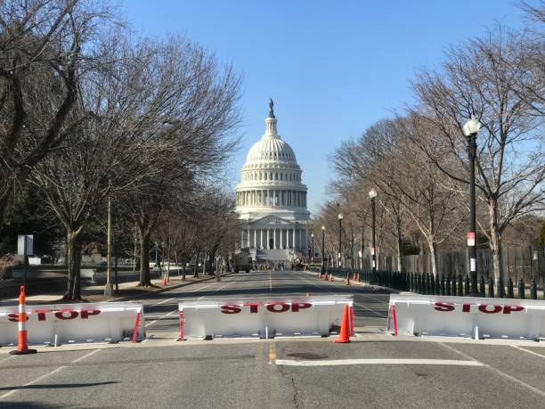 The US Capitol with increased security after the riots. The road is closed by a normally hidden bollard, and the surrounding area is covered with a 3-meter fence to keep people away. riot photos stock pictures, royalty-free photos & images