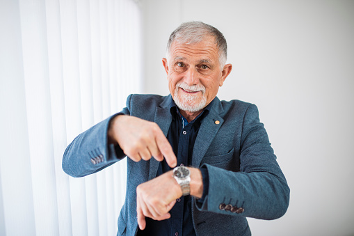 Senior man checking time on his watch at home office