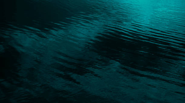 istock Dark blue green abstract background. Reflection of light on a smooth surface of water with small waves. Seascape. 1304390065