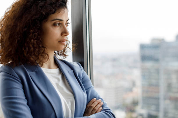 istock Young thoughtful businesswoman looking through window 1304391800
